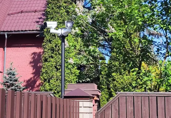 Камера и светодиодный прожектор на двухрожковом кронштейне мачты BOXFORCAM™ у ограждения частного дома