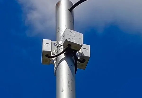 Три коробки BOXFORCAM™ закреплены вокруг металлической опоры освещения, фон — синее небо